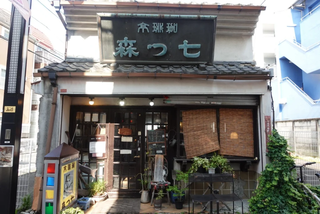 Retro wooden facade and traditional tiles of the historic Nanatsumori kissaten coffee house, a Showa-era landmark located in Koenji, Japan.