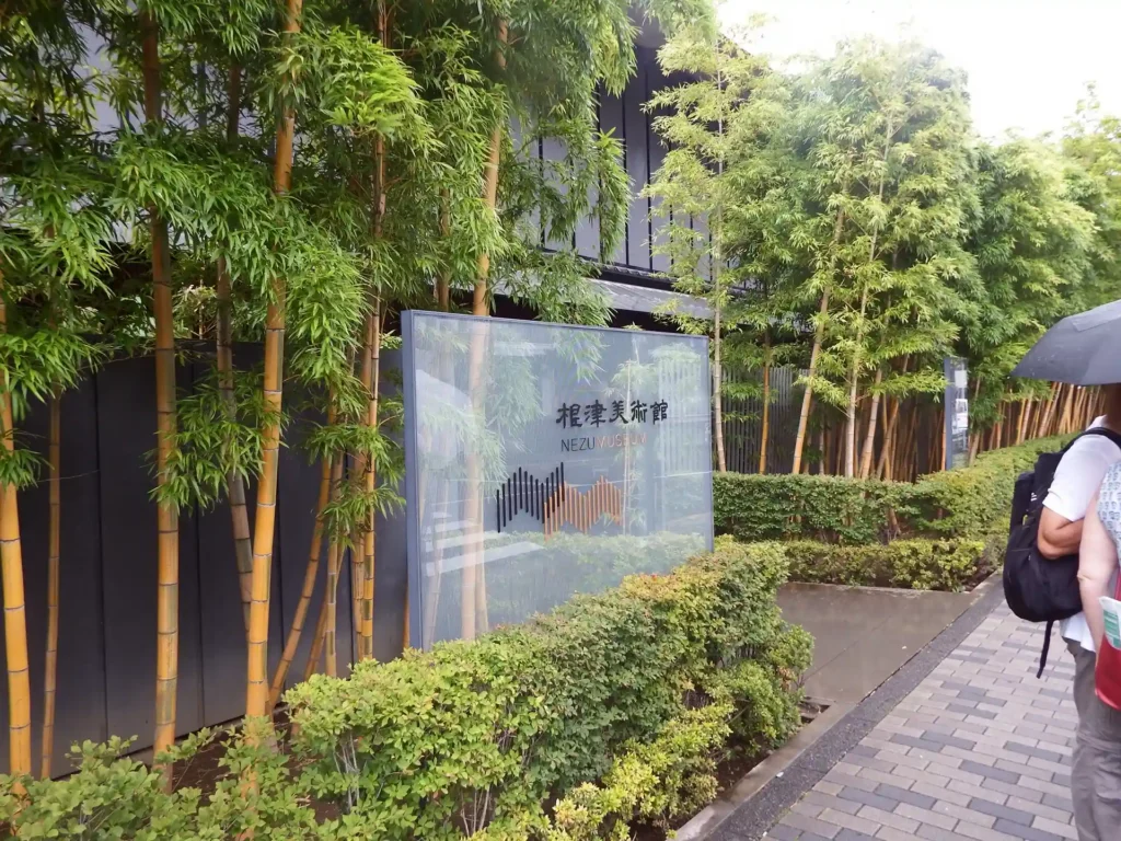 Modern glass entrance sign for the Nezu Museum surrounded by tall bamboo stalks and lush greenery in Tokyo.