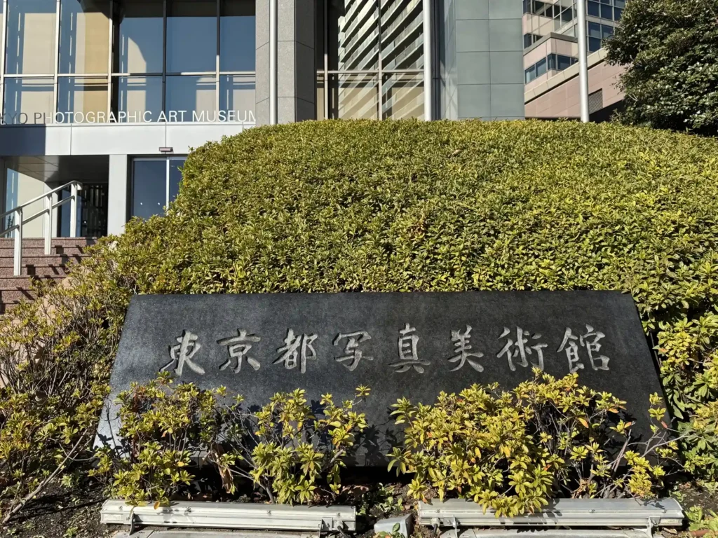 Engraved stone sign for the Tokyo Photographic Art Museum surrounded by green bushes in Yebisu Garden Place.