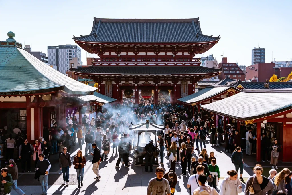 Visitors gathering around the Jokoro incense burner in front of the Hozomon Gate at Sensoji Temple.