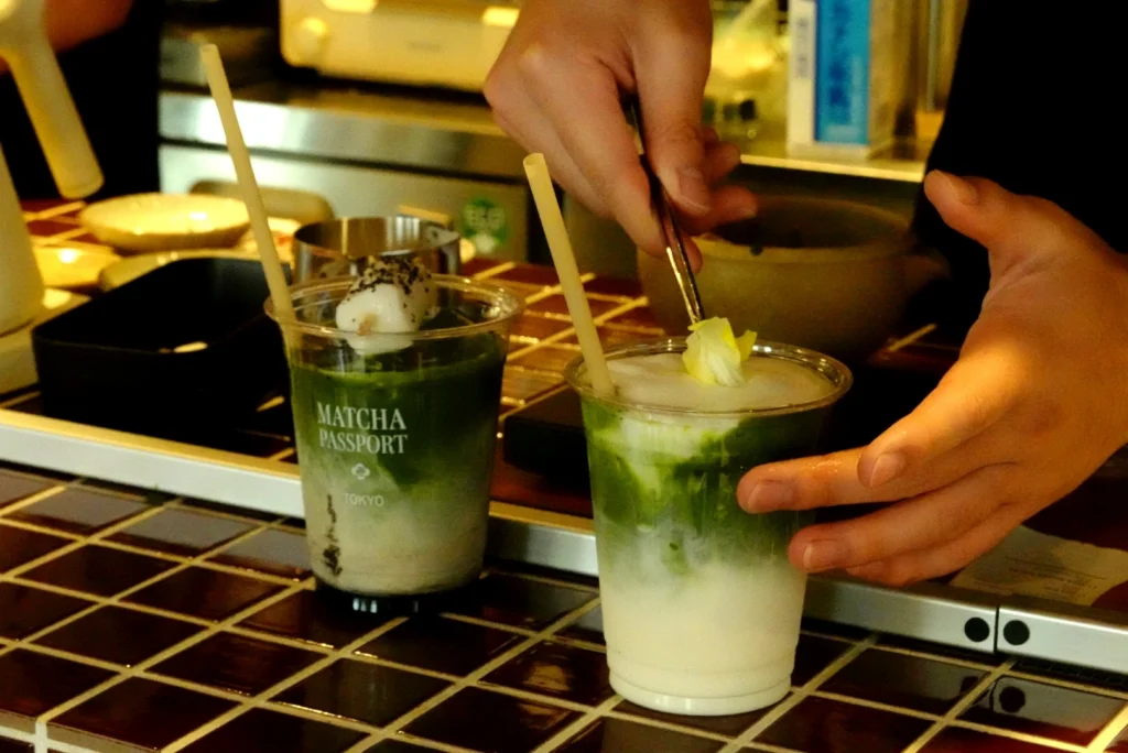 A barista preparing modern iced matcha drinks with toppings at an indie cafe in Shimokitazawa.