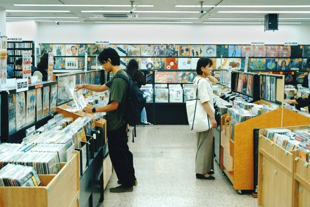 Customers browsing through an extensive collection of vinyl records at an independent music store in Shimokitazawa.
